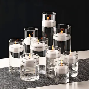 Elegante glazen cilindervazen met witte drijvende kaarsen voor romantische tafeldecoratie