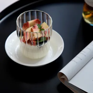 Elegant striped borosilicate glass cup filled with fresh fruit on a white saucer background