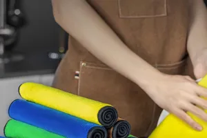 Detalle de paños de limpieza de microfibra gruesos y coloridos en el entorno de una cocina.