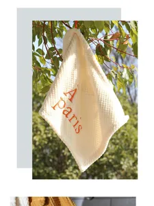 Detailed macro view of embroidered 'À paris' text on soft white coral fleece towel