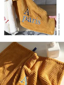 Close-up detail of absorbent ochre coral fleece hand towel with À paris embroidery