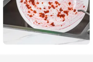 Primer plano de un plato de cerámica blanca sucio con restos de comida en el fregadero