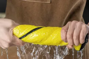 Primer plano escurriendo un paño de limpieza amarillo con salpicaduras de agua real