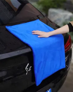 Primer plano de una toalla de limpieza de microfibra azul gruesa para coche en superficie negra