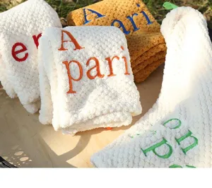 Close-up view of embroidered alphabet letters on thick coral fleece hanging hand towels.