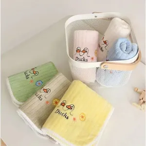 Collection of soft colorful children's face towels with cute duck embroidery in a white basket