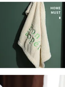 Macro view of coral fleece kitchen hand towel with green Bon Appetit embroidery detail.
