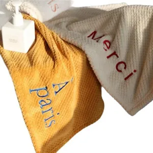 Soft coral fleece kitchen hand towels featuring chic embroidered French text decoration.