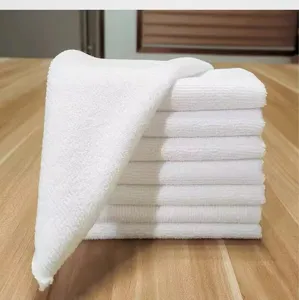 Detailed macro view of high-quality white microfiber square towels stacked on a wooden surface