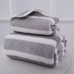 Detail of folded grey and white striped coral fleece bath towels with soft texture.