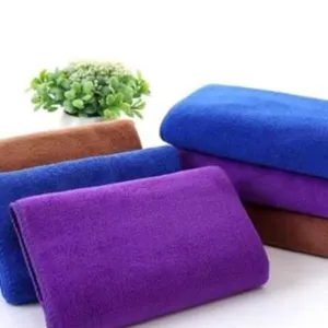 Vista detallada de paños de limpieza de microfibra doblados en colores morado, azul y marrón.