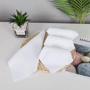 Detailed view of white textured square towels arranged on a woven tray with green plants