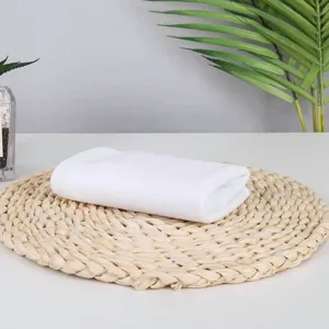Detail of a soft white disposable square towel folded on a natural woven mat