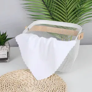White disposable square towel absorbent cleaning cloth draped over a mesh basket detail