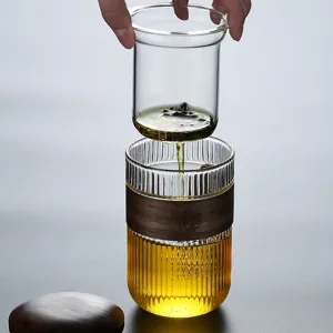 Transparent ribbed glass tea cup set with dark wooden sleeve and infuser strainer