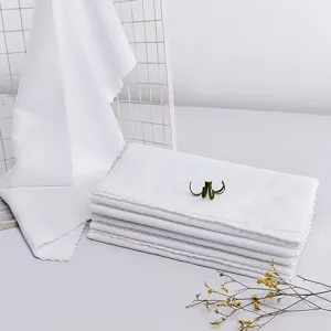Close-up of premium thickened white microfiber towels with soft scalloped edge details.
