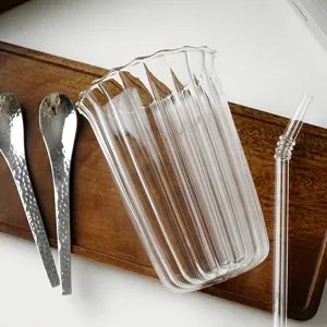 Elegante bicchiere in vetro borosilicato a coste con cannuccia trasparente su vassoio in legno