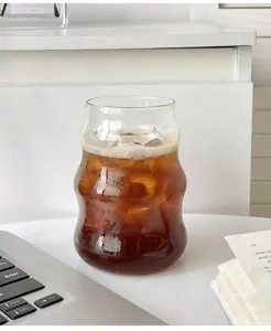 Detaillierte Nahaufnahme einer wellenförmigen Glastasse mit Eiskaffee auf einem weißen Tisch