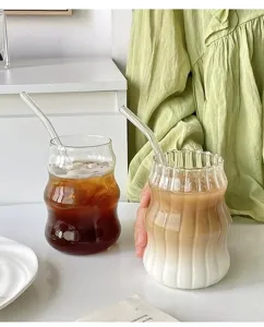 Detailaufnahme gewellter Glasbecher mit Eiskaffee und cremigen Latte-Getränken darin.