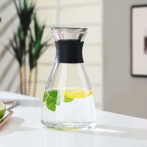 Detail shot of a transparent glass water pitcher with black silicone grip, ideal for juice and tea.