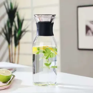 Detail view of Scandinavian style glass cold water pitcher with black lid, lemon and mint.
