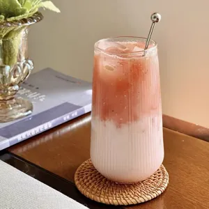 Elegant ribbed high borosilicate glass cup with a layered drink served on a woven rattan coaster