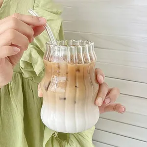Eleganter gerippter Glas-Kaffeebecher mit Eislatte und Glasstrohhalm in der Hand gehalten