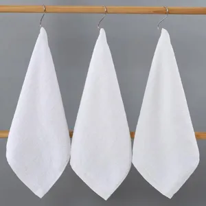 Macro view of three white pure cotton square hand towels hanging on metal hooks for bathroom