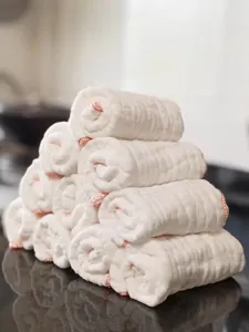 Macro detail of multi-layer white cotton gauze dishcloths with pink stitched edges