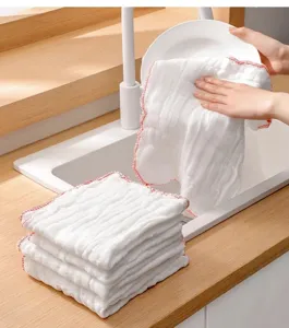 Detail showing a hand using the white cotton gauze dishcloth to wipe a ceramic plate.