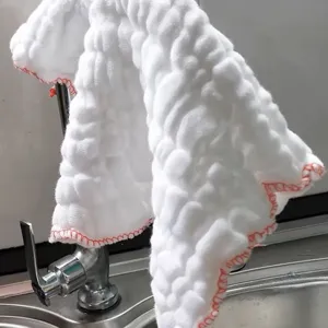 Thickened absorbent white cotton dishcloth with red border hanging on a kitchen faucet