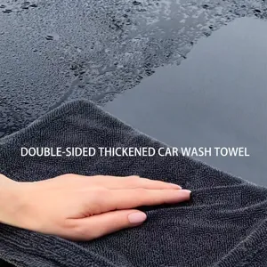 Macro detail of a thick gray microfiber towel absorbing water from a car body surface.