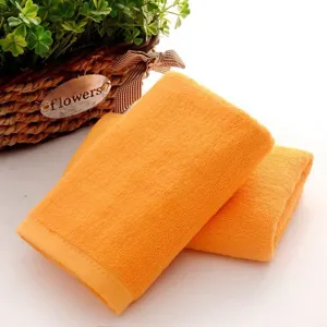 Two soft orange cotton square towels stacked next to a decorative flower basket.