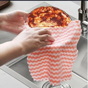 Detail shot of pink wavy coral fleece dishcloth cleaning a greasy plate in a sink