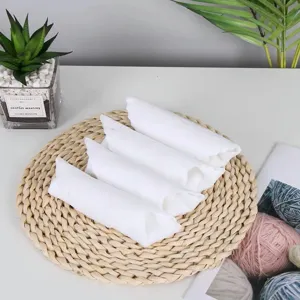 Close-up shot of four rolled absorbent white disposable mini towels on a rustic woven mat