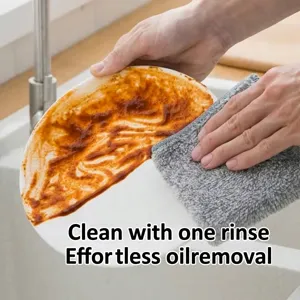 Detalle de un paño de fibra de carbón de bambú gris limpiando aceite de un plato blanco.