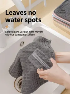 Close-up detail of a dark gray waffle weave microfiber cleaning cloth wiping a glass cup