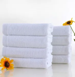 Close-up detail showing the soft texture of white cotton towels stacked neatly with yellow flowers.