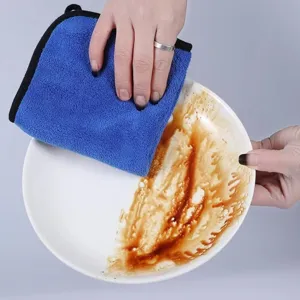 Paño de microfibra azul grueso limpiando manchas de aceite en un plato de cerámica.