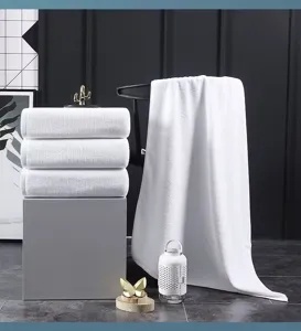Detailed view of thick white cotton hotel bath towels stacked and draped in a modern setting
