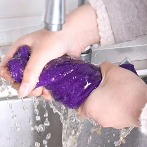Gros plan d'un chiffon de nettoyage en microfibre violet épais rincé sous un robinet