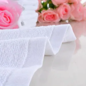 Macro view of soft white cotton towel texture showing absorbent loop pile details.