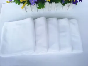 Detail showing folded disposable white microfiber towels for industrial cleaning use.