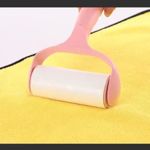 Close-up view of a pink handheld lint roller cleaning a yellow microfiber towel surface