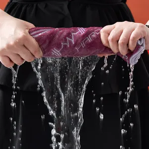 Primo piano di un asciugamano sportivo viola assorbente strizzato con vivaci schizzi d'acqua