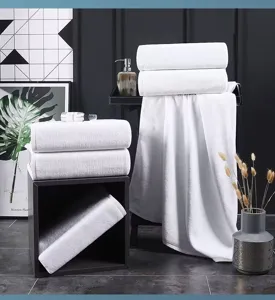Group of premium thick white cotton bath towels displayed in a modern luxury bathroom.