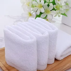 Detail view of soft white cotton washcloths neatly folded on a natural wooden tray.