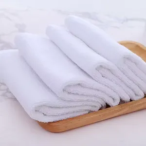 Close-up of soft white cotton square towels folded neatly on a wooden tray