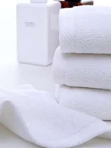 Close-up of white cotton square towels showing soft looped texture and neat edges.