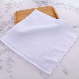 Close-up detail of a soft white pure cotton small square towel presented on a wooden tray
